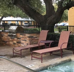 Braun Station Apartments in San Antonio Two lounge chairs next to a hot tub and grill in Braun Station Apartments for rent in San Antonio.